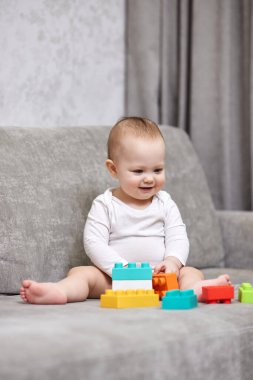 Sevimli bebek evde renkli oyuncak bloklarıyla oynuyor.