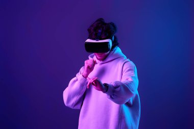 man in sweatshirt using virtual reality glasses and playing video games on blue background. Neon lighting