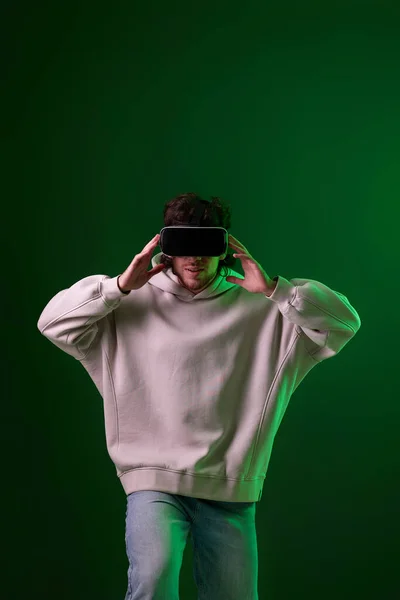 Man Sweatshirt Using Virtual Reality Headset Green Background Neon Lighting — Zdjęcie stockowe