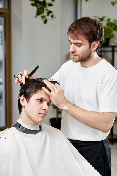 在理发店拜访专业理发师的英俊年轻人 — 图库照片