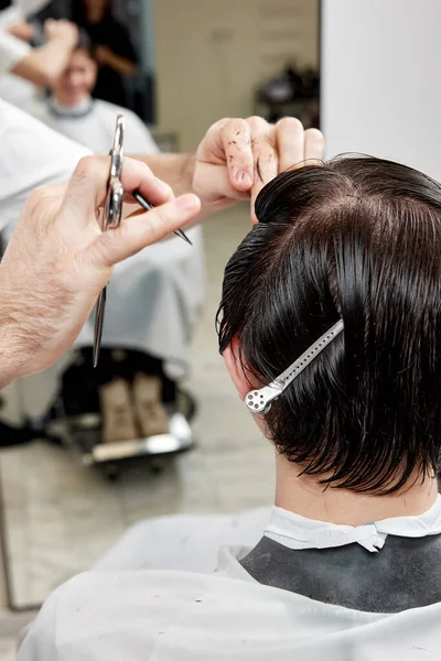 在现代理发店为年轻的高加索客户服务的专业男性理发师 — 图库照片