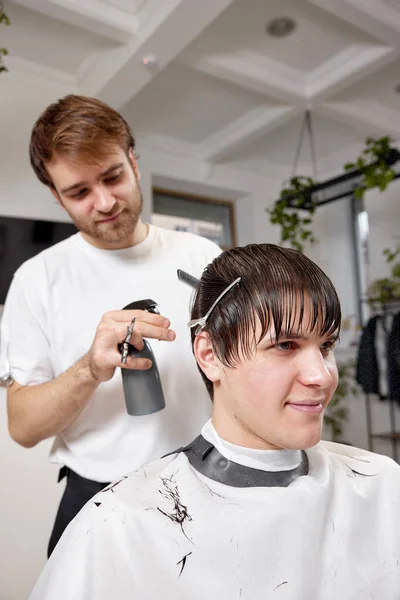 理发店的专业男性理发师用梳子和喷雾器理发的快乐男人 — 图库照片