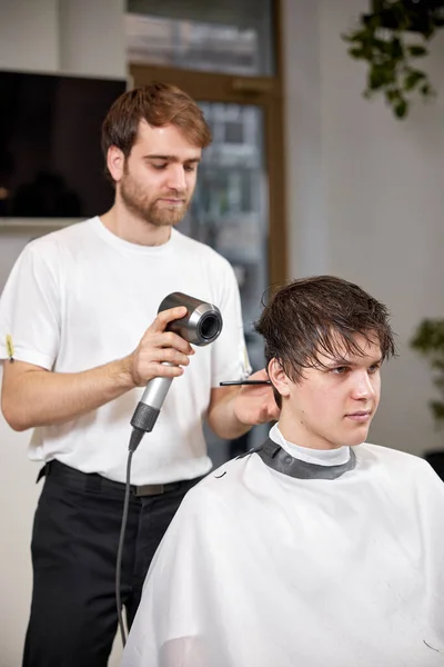 在理发店与有吹风机的男性客户一起工作时的专业理发师 理发店理发 — 图库照片