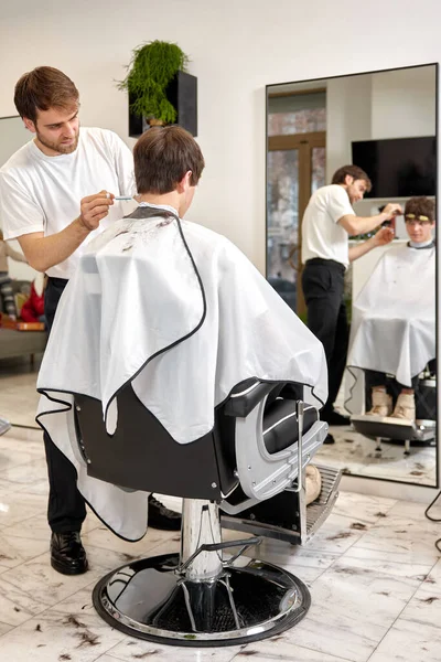 年轻的高加索男子在理发店被专业的男性理发师理发 — 图库照片