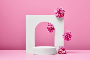 Pembe çiçekli beyaz podyum ve pastel pembe arka planda izole edilmiş zarif kemer. sunum için sahne kozmetik veya güzellik ürünü