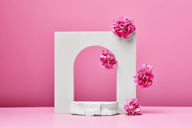 Pembe çiçekli beyaz podyum, taş ve zarif kemer pastel pembe arka planda izole. sunum için sahne kozmetik ürünleri