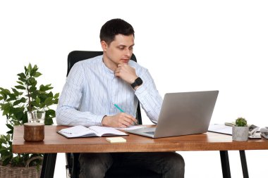 Genç adam, beyaz arka plandaki masada online iş için dizüstü bilgisayar kullanıyor.