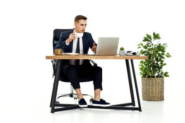 Genç arkadaş canlısı Freelancer müşteriyle video görüşmesi yapıyor, masada oturuyor, bilgisayarını kullanıyor.