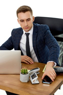 Bilgisayarla çalışan yakışıklı bir iş adamı ve akıllı telefon kullanıyor.