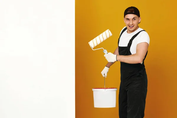Ευτυχισμένος Άνθρωπος Ρούχα Εργασίας Κλείνει Μάτι Και Ζωγραφίζει Λευκούς Τοίχους — Φωτογραφία Αρχείου