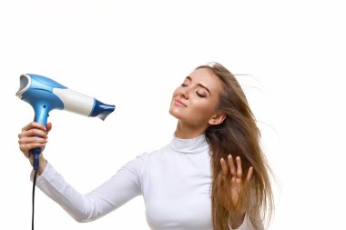 Beyaz arka planda uzun saçlarını kurutan neşeli bir kızın portresi.