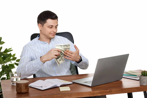若いハンサムなビジネスマンがノートパソコンで働いてお金を持って机の上で椅子に座って — ストック写真