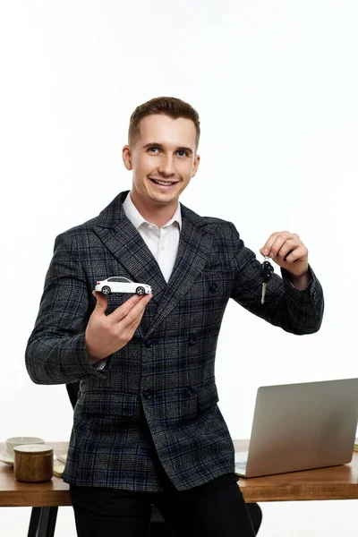 Successful caucasian businessman holding toy car and key in the office. Car dealerships offer car . Car insurance