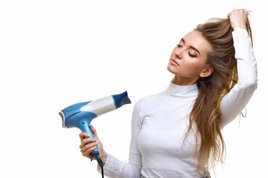 Beyaz arka planda izole ettiğim kurutucuyla güçlü, sağlıklı saçları olan güzel genç bir kadın.