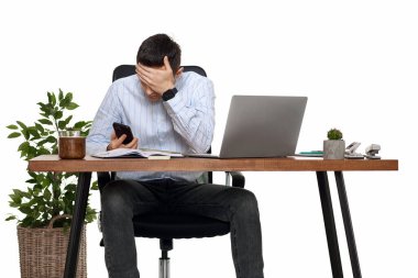 üzgün iş adamı dizüstü bilgisayarla çalışıyor ve müşteriyle telefon görüşmesi yapıyor.
