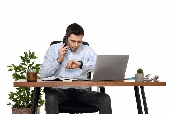 surprised businessman looking at watch while working with laptop and having phone conversation with client