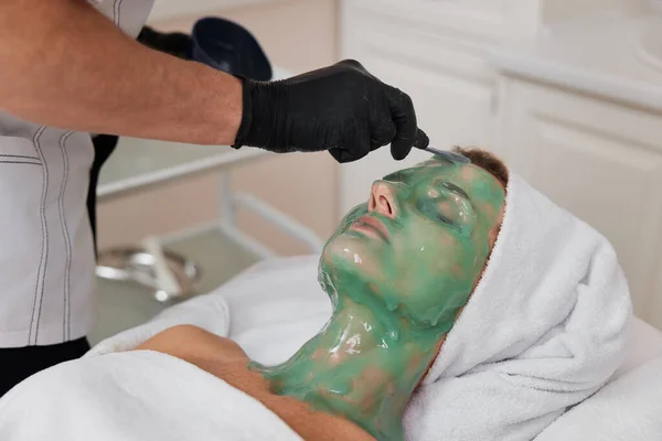 美容师在温泉沙龙的美女脸上涂上绿色的海藻酸钠面膜 温泉治疗 — 图库照片