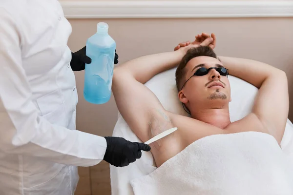 Koruyucu Gözlüklü Genç Adam Klinikte Kol Çukuru Lazer Epilasyonundan Geçiyor — Stok fotoğraf
