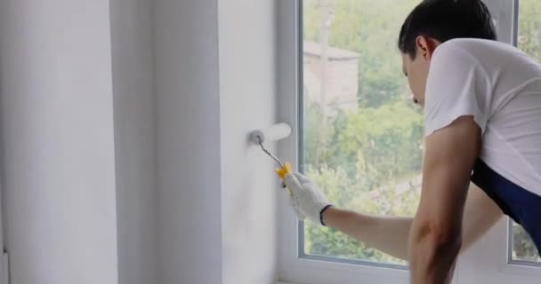 House Ζωγράφος Μπλε Φόρμα Ζωγραφίζει Τοίχο Λευκό Χρώμα Ρολό Ενώ — Αρχείο Βίντεο