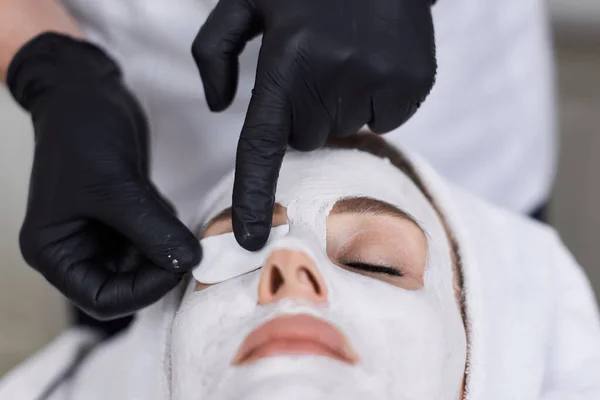 男性美容師は美容室の美人の顔にマスクを適用します 顔のスキンケアのコンセプト — ストック写真
