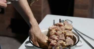 Adam şişte barbekü pişiriyor, şişte et parçaları yiyor.