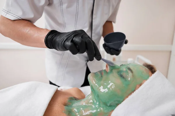 Kosmetikerin Trägt Grüne Alginatmaske Auf Das Gesicht Der Schönen Frau — Stockfoto