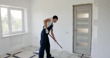 Üniformalı boyacı odayı yenilerken duvarları beyaza boyuyor.