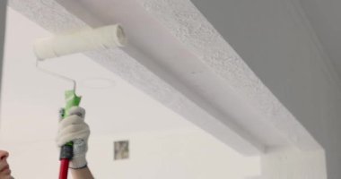 Tamirci odayı yenilerken duvarı beyaza boyuyor.