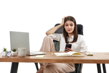 Güzel, mutlu bayan yönetici dizüstü bilgisayarla çalışıyor ve beyaz arka planda telefon kullanıyor.