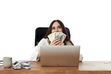 Mutlu iş kadını dizüstü bilgisayarda çalışıyor ve elinde para tutuyor.