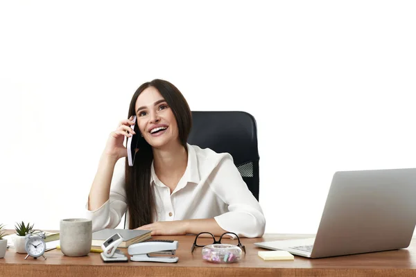 漂亮的 快乐的女商人在办公室里用笔记本电脑和电话交谈 — 图库照片