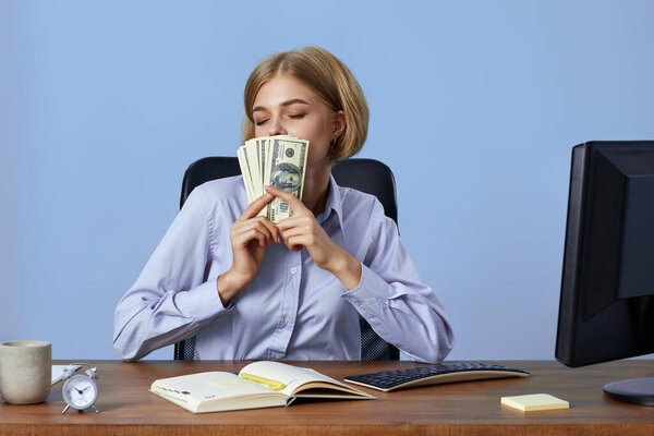 happy blonde business woman covering face with money dollars in office. Achievement business