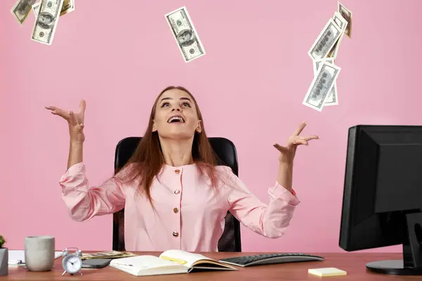pretty businesswoman throwing money on pink background. banknotes fly in the air
