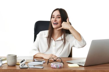 Gülümseyen güzel bir kadın dizüstü bilgisayar kullanıyor ve telefonda konuşuyor. Ara beni.