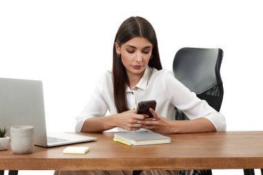 Bilgisayarla çalışan ve beyaz arka planda telefon kullanan güzel bir iş kadını.