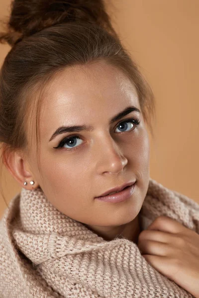 米色背景针织围巾的年轻漂亮女人的肖像 — 图库照片