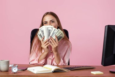 İş kadını, pembe arka planda para dolu yüzü örtüyor. Başarı işi