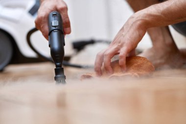 Erkek eli profesyonel temizlik buhar jeneratörüyle zemini temizliyor, ev dezenfeksiyonu...