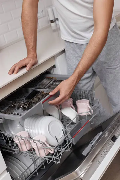 close-up, man unloading dishwasher machine in the kitchen