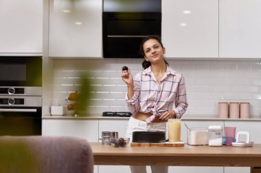 Güzel bir kadın açık modern mutfak içinde erikli turta pişiriyor. Ev yemeği yapmaktan zevk alıyorum.