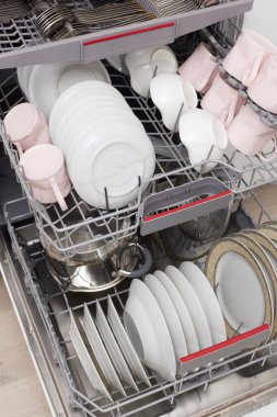 Temiz çatal bıçak, tabak, bulaşık makinesi ve beyaz modern mutfakta tabaklar. en üstteki görünüm