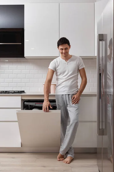 白いモダンなキッチンで食器洗いと洗濯料理を使用してハンサムな夫男 — ストック写真