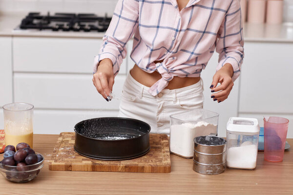 female hands preparing pie in modern kitchen, woman adding ingredients to bowl