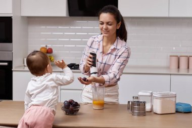 Anne ve küçük kızı modern mutfakta erikli turta hazırlıyorlar. Birlikte pişirmek.