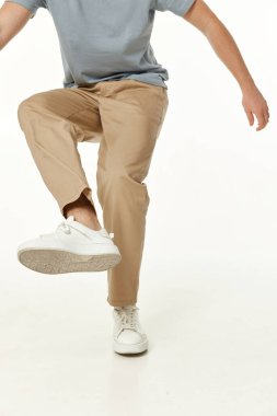 Genç adam beyaz stüdyo arka planında ayakkabıyı kameraya gösteriyor.