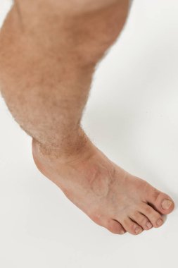 Beyaz arka planda çıplak ayaklı erkek bacakları. Vücut bakımı kavramı.