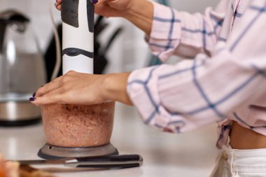 Kadın blender kullanıyor ve et öğütüyor. Kıyma hazırlama.