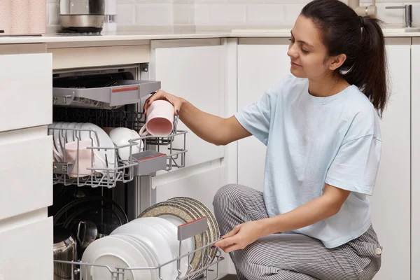 Привлекательная Женщина Разгружает Чашку Открытой Автоматической Встроенной Посудомоечной Машины Чистой — стоковое фото