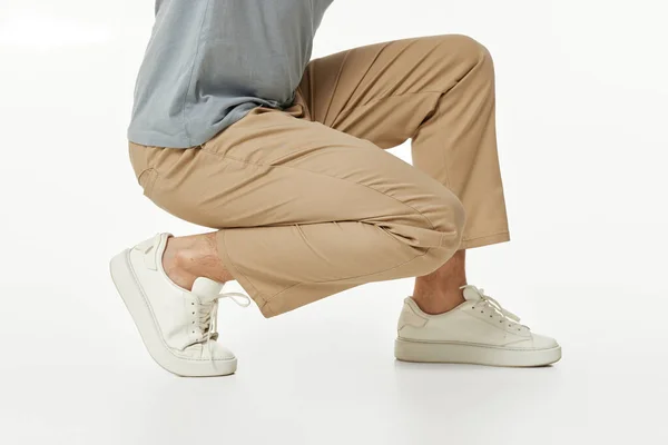 Hombre Con Zapatillas Blancas Pantalones Beige Casual Cuclillas Fondo Del —  Fotos de Stock