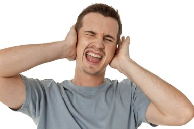 Tişörtlü beyaz adam kulaklarını beyaz arka planda kapatıyor.